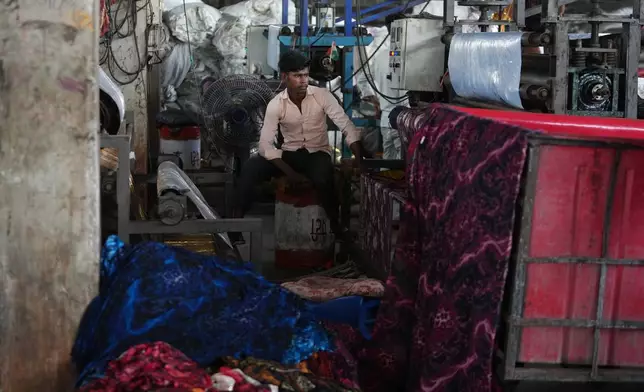A worker sits near a fan at a textile factory on a hot day in Sachin near Surat, India, Wednesday, May 27, 2026. (AP Photo/Ajit Solanki)