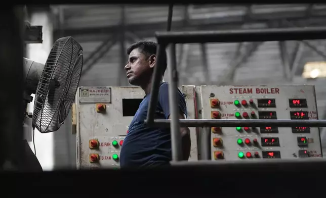 A worker stands in front of a fan on a hot day at Vinit Fabrics in Palsana near Surat, India, Tuesday, May 26, 2026. (AP Photo/Ajit Solanki)