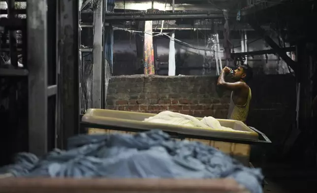 A worker drinks water at a textile factory on a hot day in Sachin near Surat, India, Wednesday, May 27, 2026. (AP Photo/Ajit Solanki)