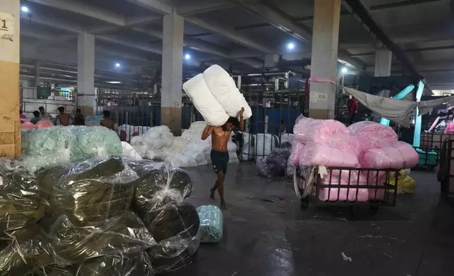 A worker carries material on a hot day at Vinit Fabrics in Palsana near Surat, India, Tuesday, May 26, 2026. (AP Photo/Ajit Solanki)
