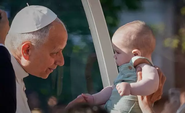 Pope Leo XIV greets a child upon arriving in the popemobile at Plaza de Cibeles for a Holy Mass and Corpus Christi procession in Madrid, Spain, Sunday, June 7, 2026, on the second day of his seven-day apostolic visit to mainland Spain and the Canary Islands. (AP Photo/Andrea Comas)