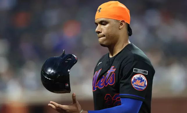 New York Mets' Juan Soto flips his helmet during a pitching change in the fifth inning of a baseball game against the Chicago Cubs, Thursday, June 25, 2026, in New York. (AP Photo/Heather Khalifa)