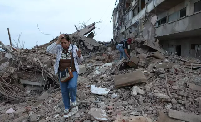 Residents walk among the rubble of building damaged in earthquakes the previous day in Catia La Mar, Venezuela, Thursday, June 25, 2026. (AP Photo/Pedro Mattey)