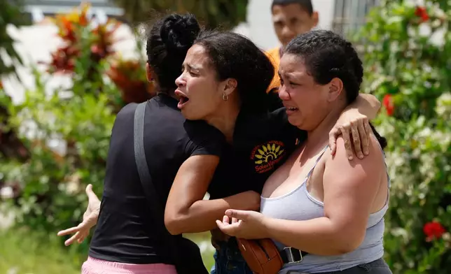 Neighbors comfort Gabriela Rojas, center, as she mourns in front of her damaged home, where two of her children died during earthquakes that struck La Guaira, Venezuela, Thursday, June 25, 2026.. (AP Photo/Pedro Mattey)