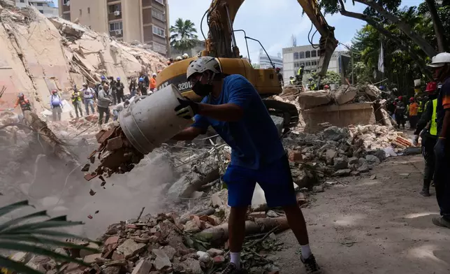 Residents help to remove rubble from a collapsed building in Caracas, Venezuela, Thursday, June 25, 2026, a day after successive powerful earthquakes struck the country. (AP Photo/Ariana Cubillos)