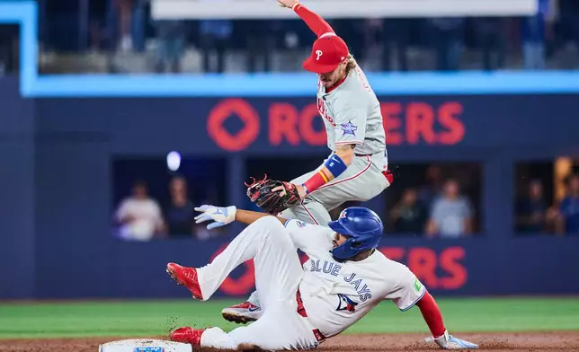 Toronto Blue Jays' Vladimir Guerrero Jr. (27) slides into Philadelphia Phillies second baseman Bryson Stott (5) as he is out at second during the third inning of a baseball game in Toronto, on Tuesday, June 9, 2026. (Sammy Kogan/The Canadian Press via AP)