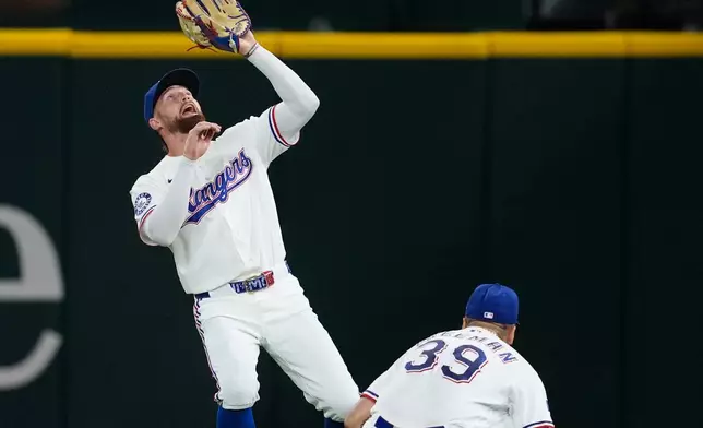 Texas Rangers second baseman Cody Freeman (39) kneels to clear the was for right fielder Brandon Nimmo who reaches up to catch a fly out by Minnesota Twins' Austin Martin in the fifth inning of a baseball game in Arlington, Texas, Monday, June 15, 2026. (AP Photo/Tony Gutierrez)
