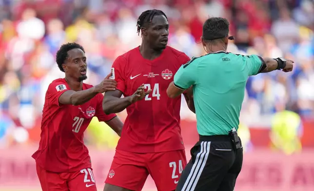 Canada's Ali Ahmed, left and teammate Canada's Promise David speak to referee Facundo Tello during the World Cup Group B soccer match between Canada and Bosnia in Toronto, Friday, June 12, 2026. (AP Photo/Stephanie Scarbrough)