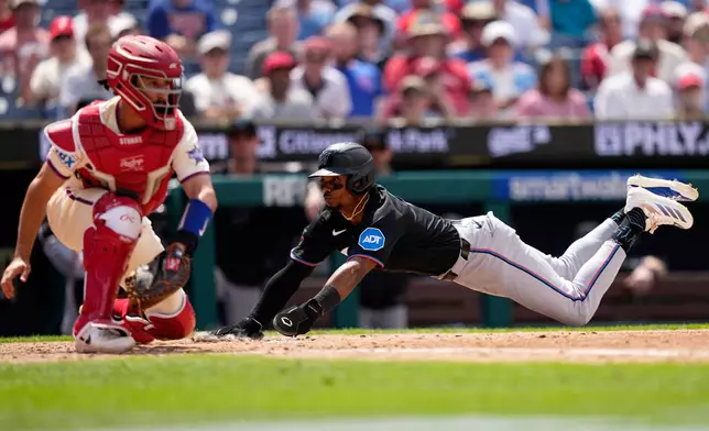 Miami Marlins' Esteury Ruiz, right, scores past Philadelphia Phillies catcher Garrett Stubbs on a sacrifice fly by Otto Lopez during the sixth inning of a baseball game Wednesday, June 17, 2026, in Philadelphia. (AP Photo/Matt Slocum)