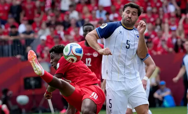 Bosnia's Sead Kolasinac (5) deflects the ball with his forearm on a shot from Canada's Jonathan David (10) during the first half of the World Cup Group B soccer match between Canada and Bosnia, Friday, June 12, 2026, in Toronto. (Frank Gunn/The Canadian Press via AP)