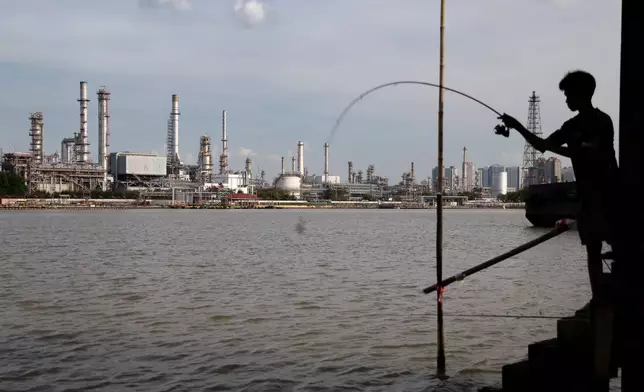 FILE - A boy fishes in front of the Bangchak Oil Refinery, home to Thailand's newest sustainable aviation fuel facility, in Bangkok on Jan. 3, 2026. (AP Photo/Anton L. Delgado, File)