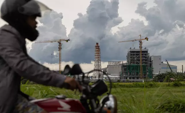 FILE - A motorcyclist drives past the South Luzon Thermal Energy Power Plant in Calaca, Batangas, in the Philippines on Oct. 4, 2025. (AP Photo/Anton L. Delgado, File)