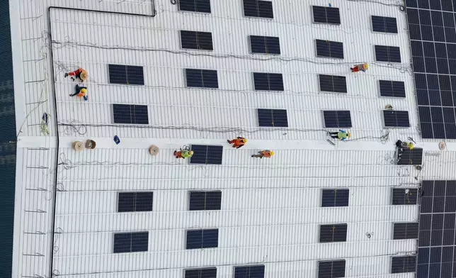 FILE - A group of workers installs solar panels on the roof of a warehouse near Jurong Island in Singapore on Oct. 6, 2025. (AP Photo/Anton L. Delgado, File)