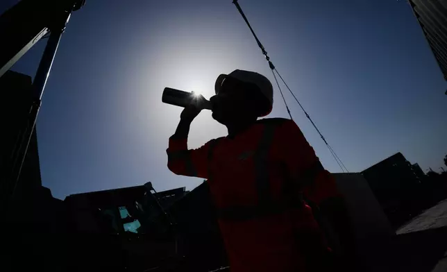 A worker drinks water on a construction site during high temperatures in Boulogne Billancourt, outside Paris, Wednesday, June 24, 2026. (AP Photo/Christophe Ena )