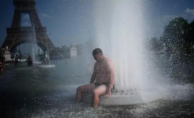A person cools off at Trocadero fountain near the Eiffel Tower during a heat wave in Paris, Wednesday, June 24, 2026. (AP Photo/Christophe Ena)