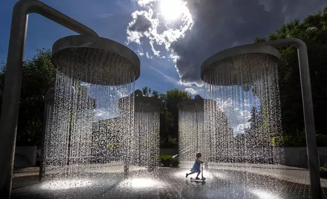A girl cools off in a public fountain in Vilnius, Lithuania, Friday, June 26, 2026. (AP Photo/Mindaugas Kulbis)