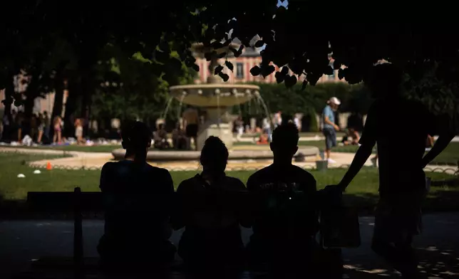 People enjoy the shade of the trees at Place des Vosges during a heat wave in Paris, Saturday, June 27, 2026. (AP Photo/Aurelien Morissard)