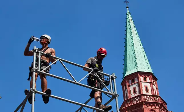 A worker drinks water as he sets up a stage for the upcoming Ironman triathlon, Frankfurt, Germany, Thursday, June 25, 2026. (AP Photo/Michael Probst)
