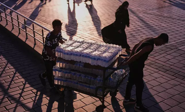 Workers deliver water bottles to a restaurant next to Galata bridge on a summer day in Istanbul, Turkey, Friday, June 26, 2026. (AP Photo/Francisco Seco)