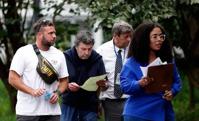 Oscar Vignale, second from left, the father of Argentine filmmaker Lucas Vignale, arrives at the Medical Examiner's Office to identify and claim the body of his son who died alongside others when two helicopters collided in midair and crashed in Rio de Janeiro, Brazil, Monday, June 15, 2026. (AP Photo/Bruna Prado)