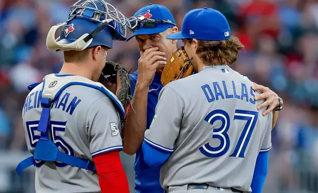 Toronto Blue Jays pitching coach Pete Walker, center, speaks with pitcher Chad Dallas (37) and catcher Tyler Heineman (55) during the third inning of a baseball game against the Atlanta Braves, Thursday, June 4, 2026, in Atlanta. (AP Photo/Erik S. Lesser)