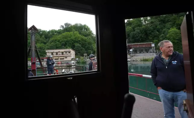 Worker Venanzio Lavelli stands as commuters board the “Da Vinci Ferry,” a hand-operated ferry based on a design sketched by Leonardo da Vinci in the 15th century, on the Adda River between the provinces of Lecco and Bergamo, in Imbersago, Italy, Thursday, June 4, 2026. (AP Photo/Luca Bruno)