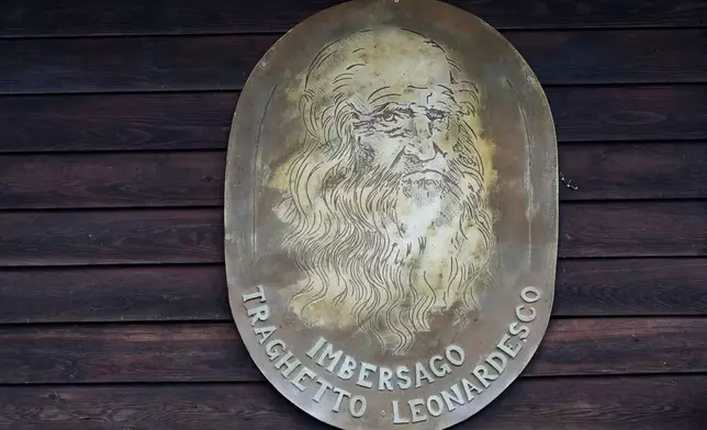 An effigy of Leonardo da Vinci hangs on the dock of the “Da Vinci Ferry,” a hand-operated ferry based on a design sketched by Leonardo da Vinci in the 15th century, on the Adda River between the provinces of Lecco and Bergamo, in Imbersago, Italy, Thursday, June 4, 2026. (AP Photo/Luca Bruno)