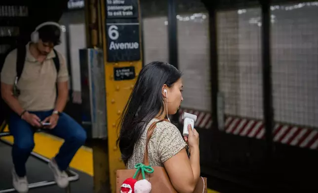 FILE - A person uses a mini electric fan as they wait on a subway platform during a heat advisory in New York, May 19, 2026. (AP Photo/Adam Gray, File)