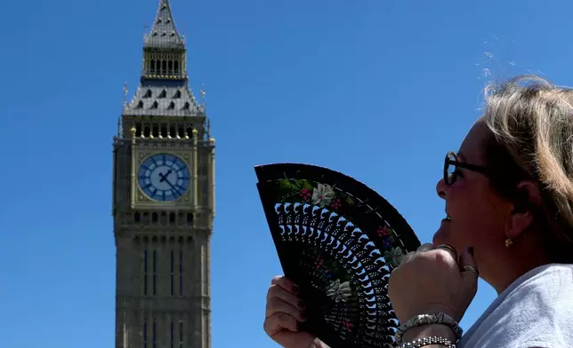 FILE - A woman cools herself outside the Palace of Westminster in London, May 26, 2026. (AP Photo/Kin Cheung, File)