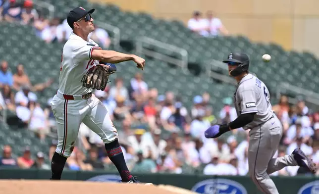 Minnesota Twins third baseman Brooks Lee, left, throws to second base for an out against the Colorado Rockies during the first inning of a baseball game Sunday, June 28, 2026, in Minneapolis. (AP Photo/Craig Lassig)