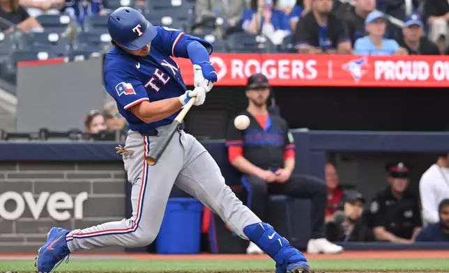 Texas Rangers designated hitter Justin Foscue hits an RBI single against the Toronto Blue Jays during the first inning of a baseball game in Toronto, Friday June 26, 2026. (Jon Blacker/The Canadian Press via AP)