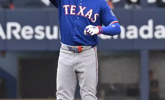 Texas Rangers' Brandon Nimmo gestures to the dugout after hitting an RBI double against the Toronto Blue Jays during the first inning of a baseball game in Toronto, Friday June 26, 2026. (Jon Blacker/The Canadian Press via AP)