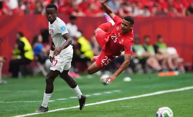 Switzerland's Luca Jaquez (25) is upended by Canada's Richie Laryea (22) during the World Cup Group B soccer match between Switzerland and Canada in Vancouver, British Columbia, Wednesday, June 24, 2026. (Darryl Dyck/The Canadian Press via AP)