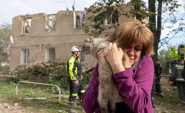 A woman holds her cat after it being found during search and rescue works in the damaged residential building following Russia's missile attack in Kharkiv, Ukraine, Saturday, June 20, 2026. (AP Photo/Andrii Marienko)
