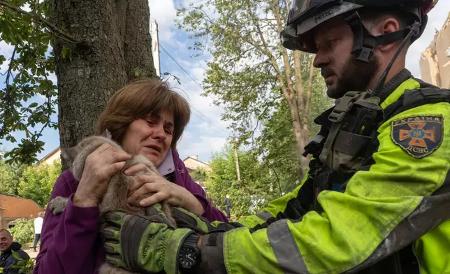 A firefighter gives a woman her cat that was found during search and rescue works in the damaged residential building following Russia's missile attack in Kharkiv, Ukraine, Saturday, June 20, 2026. (AP Photo/Andrii Marienko)