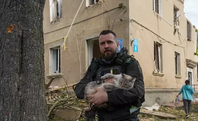 A policeman rescues a cat during search and rescue works in the damaged residential building following Russia's missile attack in Kharkiv, Ukraine, Saturday, June 20, 2026. (AP Photo/Andrii Marienko)