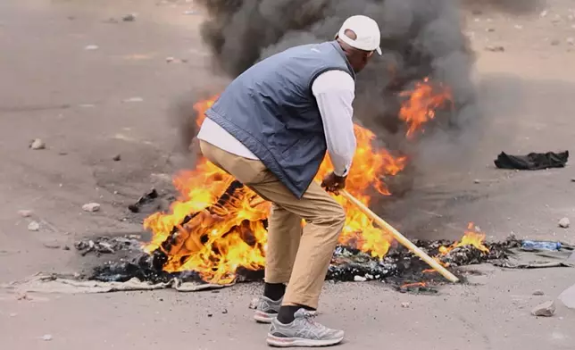 A protester sets a fire in the middle of the road during a demonstration as Congo's opposition rejects a proposed constitutional change in Kinshasa, Congo, Friday, June 12, 2026. (AP Photo/Ekutshu Yannick)