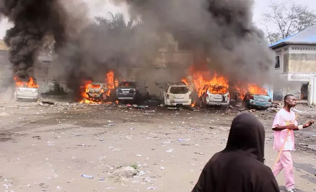 Cars burn during a demonstration as Congo's opposition rejects a proposed constitutional change in Kinshasa, Congo, Friday, June 12, 2026. (AP Photo/Ekutshu Yannick)
