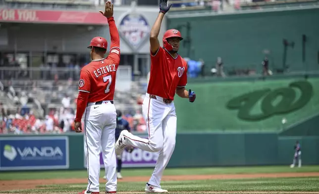 Washington Nationals' James Wood, right, celebrates his home run with third base coach Victor Estevez (7) during the first inning of a baseball game against the Seattle Mariners, Sunday, June 14, 2026, in Washington. (AP Photo/Nick Wass)