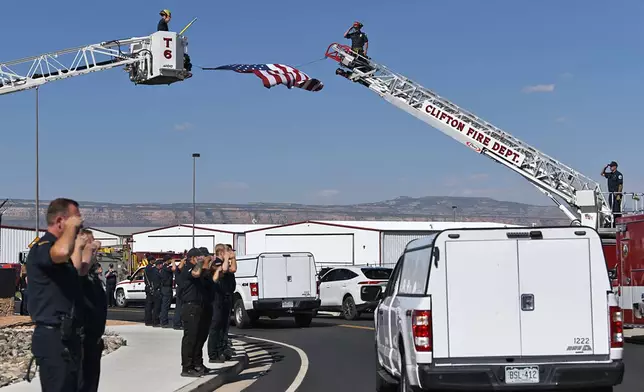 Firefighters salute as two trucks carrying the bodies of three firefighters killed while fighting the Snyder Fire are driven past in Grand Junction, Colo. Sunday, June 28, 2026. (Gretel Daugherty via AP)