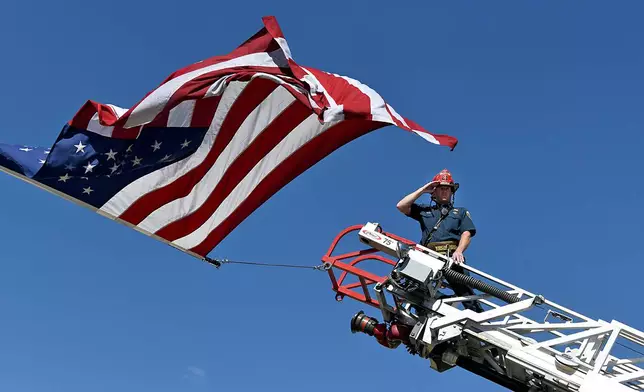 A captain with the Clifton Fire Protection District salutes the passing procession carrying the bodies of three firefighters killed while fighting the Snyder Fire in Grand Junction, Colo. Sunday, June 28, 2026. (Gretel Daugherty via AP)
