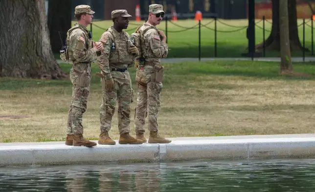 Members of the National Guard stop and look at the Lincoln Memorial Reflecting Pool Sunday, June 21, 2026, on the National Mall in Washington. (AP Photo/Jon Elswick