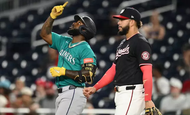 Seattle Mariners' Randy Arozarena, left, gestures at first base after he hit a single during the second inning of a baseball game next to Washington Nationals first baseman Luis Garcia Jr., right,, Friday, June 12, 2026, in Washington. (AP Photo/Nick Wass)