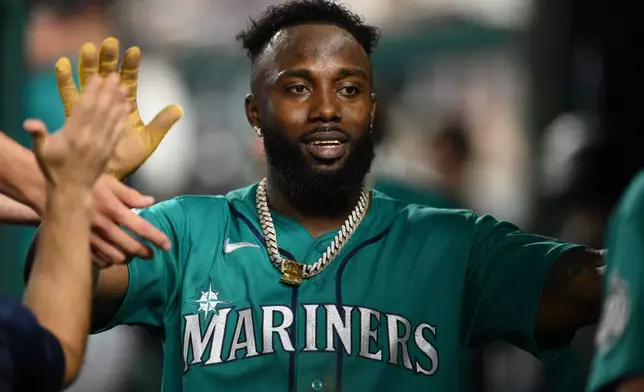 Seattle Mariners' Randy Arozarena celebrates in the dugout after he scored on a triple by Dominic Canzone during the second inning of a baseball game, Friday, June 12, 2026, in Washington. (AP Photo/Nick Wass)