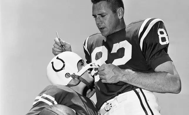 FILE - David Driscoll, 9, of Baltimore, wearing a copy of a Baltimore Colt uniform, gets an autograph on his helmet from end Raymond Berry at the Westminster training camp of the NFL club, Aug. 2, 1965. (AP Photo/William A. Smith, file)