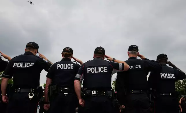 Police salute during a procession with the body of Toronto Police Const. Marc Pinizzotto, who was killed in the line of duty, at the Chief Coroner's office in Toronto, Thursday, June 11, 2026. (Sammy Kogan/The Canadian Press via AP)