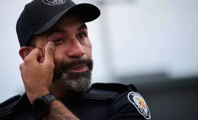 A police officer wipes away a tear after a procession with the body of Toronto Police Const. Marc Pinizzotto, who was killed in the line of duty, at the Chief Coroner's office in Toronto, Thursday, June 11, 2026. (Sammy Kogan/The Canadian Press via AP)