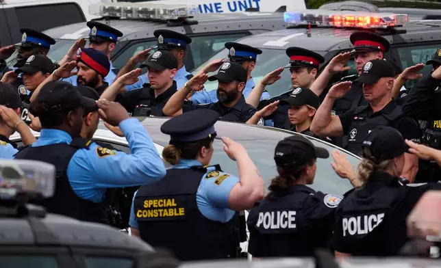 Police salute during a procession with the body of Toronto Police Const. Marc Pinizzotto, who was killed in the line of duty, at the Chief Coroner's office in Toronto, Thursday, June 11, 2026. (Sammy Kogan/The Canadian Press via AP)