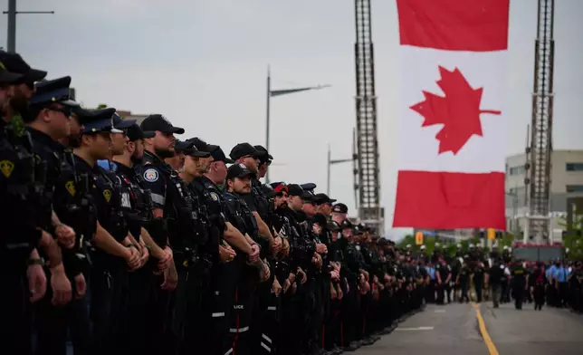 Police stand by for the arrival of a procession with the body of Toronto Police Const. Marc Pinizzotto, who was killed in the line of duty, at the Chief Coroner's office in Toronto, Thursday, June 11, 2026. (Sammy Kogan/The Canadian Press via AP)