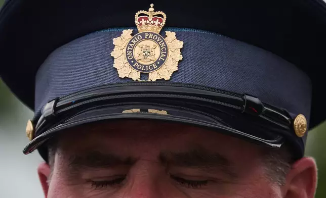 A police officer pauses as he stands for the arrival of a procession with the body of Toronto Police Const. Marc Pinizzotto, who was killed in the line of duty, at the Chief Coroner's office, in Toronto, Thursday, June 11, 2026. (Sammy Kogan/The Canadian Press via AP)